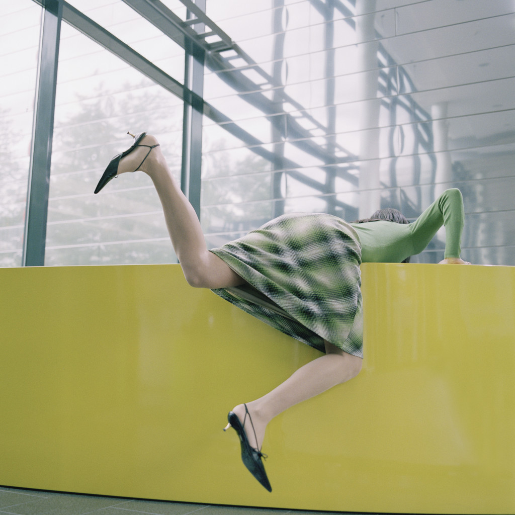 Businesswoman Awkwardly Bending over Yellow Counter